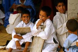 Image du Maroc Professionnelle de  Sous une tente on découvre la méthode traditionnelle de l’enseignement et l’apprentissage du saint coran prodigués aux enfants. Les jeunes récitent les sourates devant le Fkih (instituteur) qui écoute attentivement les versets ainsi récités, Samedi 18 septembre 2006, aux environ de Tan Tan dans un site désertique sur lequel la ville, a toujours accueilli la majorité des tribus et des grandes familles nomades du désert lors d'un grand Moussem, danses chants, course de chameaux et fantasia font partie des festivités. (Photo / Abdeljalil Bounhar)

 